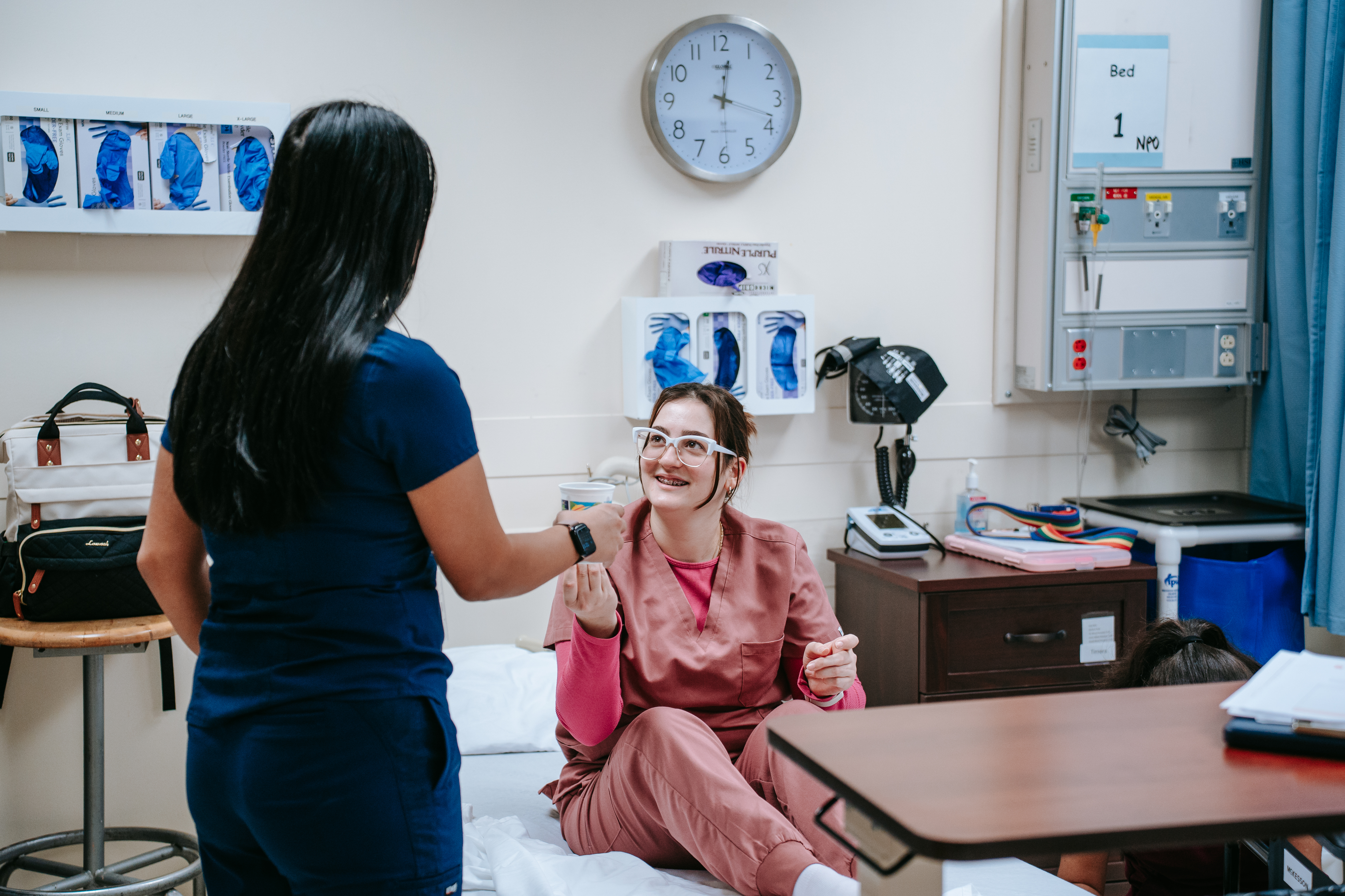 PN Student helping patient in hospital bed